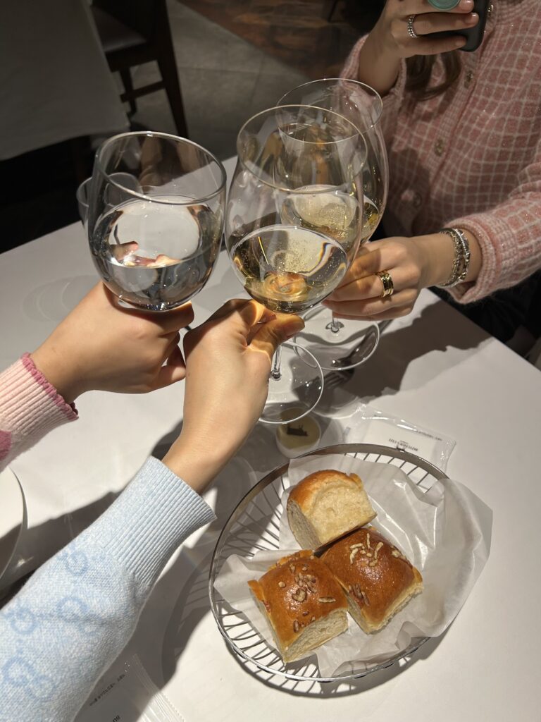 A celebratory toast between friends and family at a premium Gangnam restaurant, capturing the vibrant and inclusive dining culture of modern Seoul.