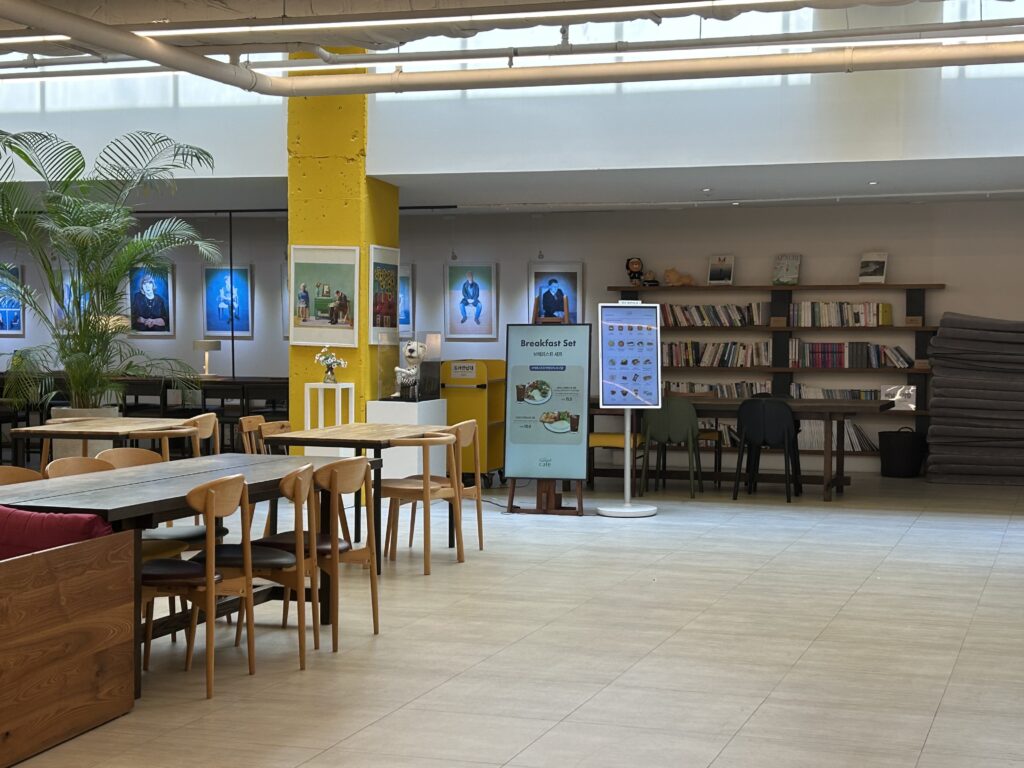 A cozy book cafe area inside Club K Seoul Jjimjilbang, with shelves full of diverse books for visitors to enjoy while relaxing.