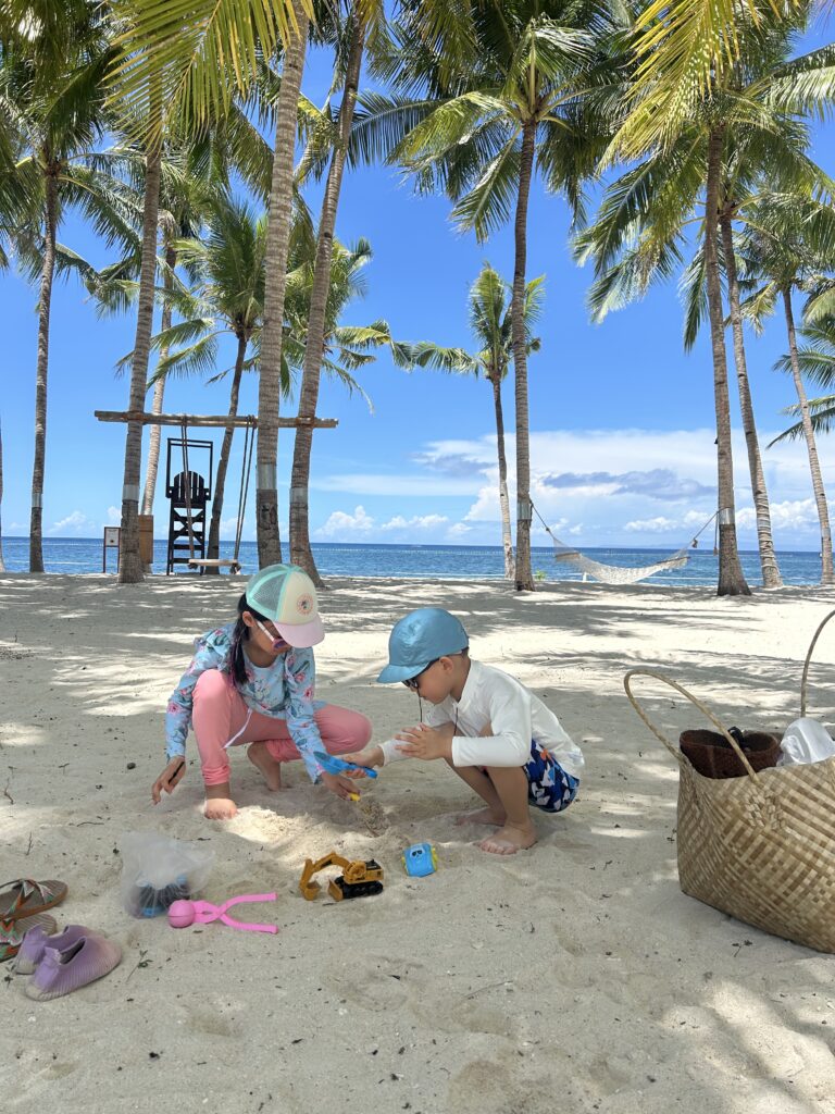 Children playing on the pristine white sand beach just a three-minute walk from the resort rooms at South Palms Resort Panglao.