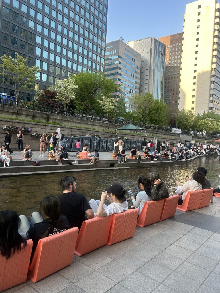 Seoul Travel Guide: Locals and international travelers reading books on fun-design chairs at the open-air Seoul Outdoor Library along Cheonggyecheon Stream.