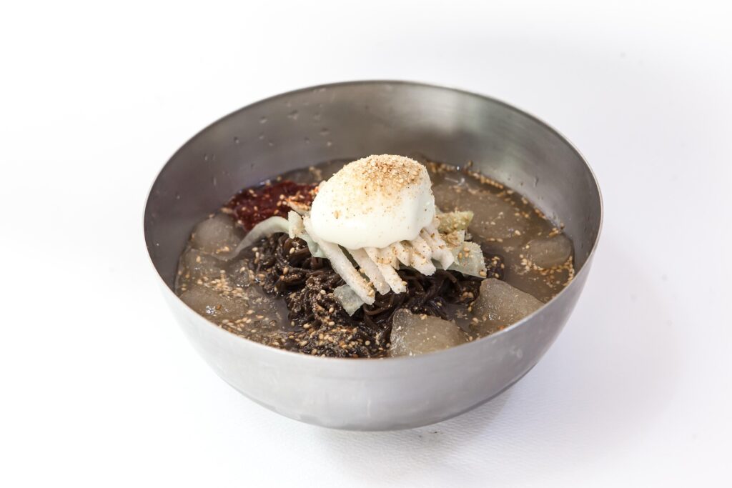 Bowl of spicy Hamhung Naengmyeon, featuring chewy noodles and tangy red chili sauce