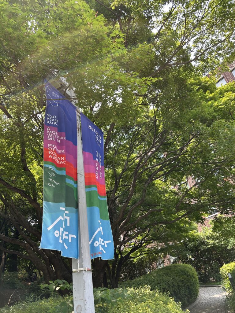 A vertical banner featuring iconic colorful abstract artwork by Yoo Youngkuk hanging outside the building to welcome visitors to a Seoul free exhibition.