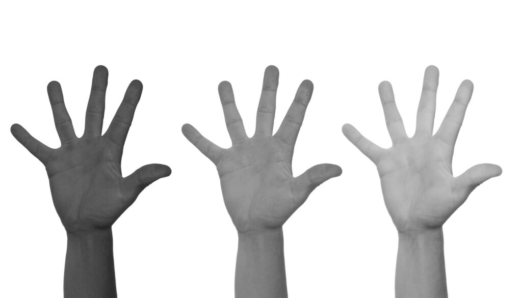 Hands of diverse skin tones raised together, illustrating cultural differences and diversity as BTS Grammy Boycott